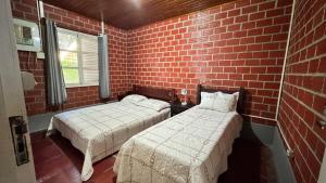 a room with two beds and a brick wall at Casa da Paz - Gravatá in Gravatá +18 photos