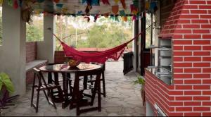 a patio with a table and chairs and a hammock at Casa da Paz - Gravatá in Gravatá