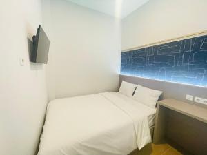 a small bedroom with a white bed and a tv at Cana's Boarding Ciledug in Pasarjumahat-Kulon