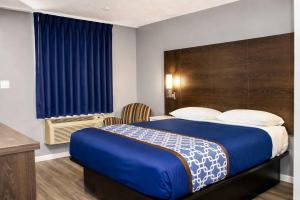 a bedroom with a large bed with a blue blanket at Masters Inn Augusta at Washington Road in Augusta