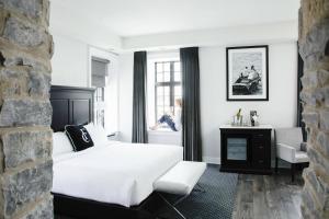 a bedroom with a white bed and a person sitting in a window at Frontenac Club, an Ascend Collection Hotel in Kingston