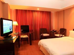 a hotel room with a bed and a flat screen tv at Hedong Hotel in Shenzhen