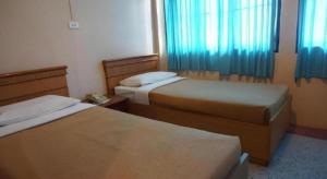 a hotel room with two beds with blue curtains at Supak Hotel in Kalasin