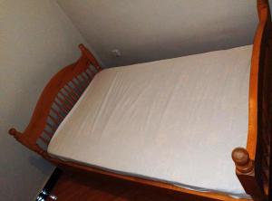 a wooden bed with a white mattress on it at Roadhouse in Jinja