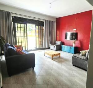 a living room with two couches and a red wall at Roadhouse in Jinja