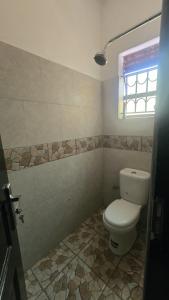 a bathroom with a toilet and a window at Roadhouse in Jinja
