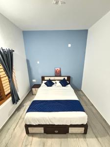 a bedroom with a large bed with blue walls at Zak Holidays Wayanad in Wayanad