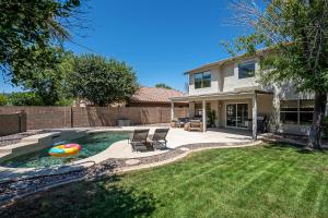 a backyard with a pool with two chairs and a house at Dos Palmas - Gilbert Poolside Retreat in Gilbert