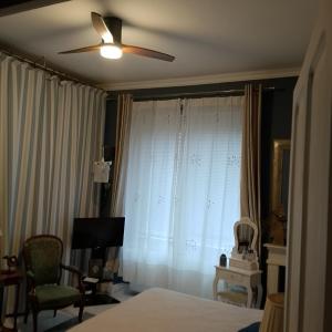 a bedroom with a ceiling fan and a window with curtains at Chambre d'hôtes Bounty - terrasse, cuisine privée, garage in Olliergues