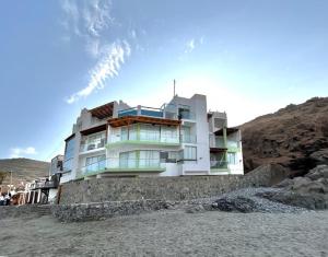 a building on the beach next to a hill at Nutria Apt in Cerro Azul with access & ocean view in Cerro Azul