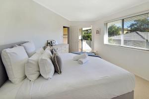 a white bedroom with a large white bed with pillows at Advance Place in Sunrise Beach