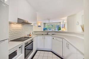 a white kitchen with white cabinets and a sink at Park Cove Apartments in Noosa Heads