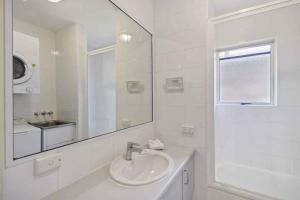 a white bathroom with a sink and a mirror at Park Cove Apartments in Noosa Heads +4 photos