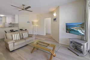 a living room with a couch and a tv at Park Cove Apartments in Noosa Heads
