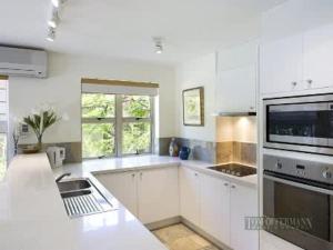 a white kitchen with a sink and a microwave at Alderly Terrace in Noosa Heads