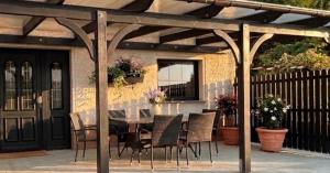 a dining table and chairs under a wooden pergola at Ferienhaus Eichenallee in Massow