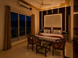 a bedroom with a bed and a table and a window at Mountain View Retreat in Yog Tapovan in Rishīkesh