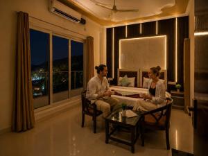 a man and woman sitting on a couch in a living room at Mountain View Retreat in Yog Tapovan in Rishīkesh +6 photos
