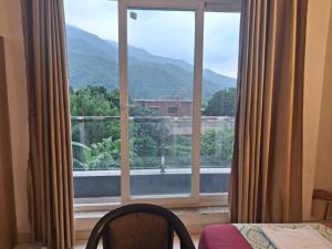 a room with a large window with a mountain view at Mountain View Retreat in Yog Tapovan in Rishīkesh
