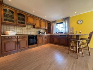 a large kitchen with wooden cabinets and a table at Ferienhaus Eichenallee in Massow