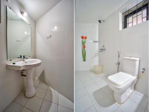 a white bathroom with a toilet and a sink at Baga Wave Edge Cottages in Baga