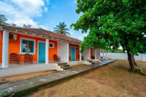 a house with orange and blue doors and a tree at Baga Wave Edge Cottages in Baga