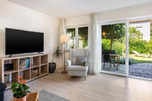 a living room with a flat screen tv and a chair at Charmantes Haus mit eigenem Garten in Prien am Chiemsee