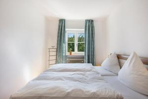 a white bed in a bedroom with a window at Charmantes Haus mit eigenem Garten in Prien am Chiemsee