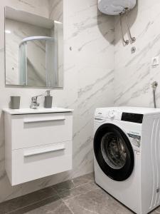 a white bathroom with a washing machine and a sink at Central Аpartment Foca with garage in Foča