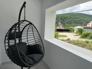 a hanging chair in a room with a window at Păușa Residence in Păuşa