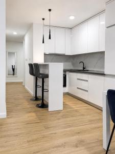 a kitchen with white cabinets and a black chair at Central Аpartment Foca with garage in Foča