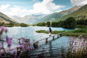 a person sitting on a dock in a lake at Chalet Nufenen in Ulrichen