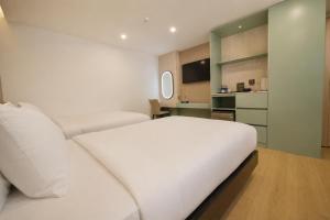 a bedroom with a white bed and a television at Y Hotel Lý Hồng Thanh in Can Tho