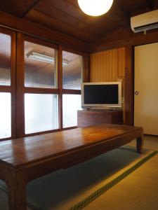 a living room with a tv and a wooden table at うみうたう in Yuwan