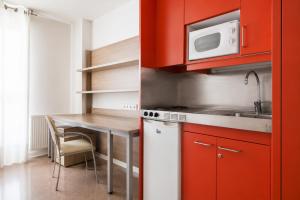 a kitchen with red cabinets and a table with a microwave at Residencia Universitaria Resa Manuel Agud Querol in San Sebastián