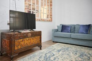 a living room with a tv on a dresser with a couch at The Merredin Treasury Cottage in Merredin