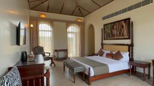 a bedroom with a large bed and a desk and a desk at RajVana, Ranthambore in Khilchipur