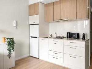 a kitchen with white cabinets and a white refrigerator at Elevated CBD Retreat - Views & Pool & Sauna! in Melbourne +13 photos