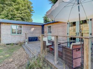 a cabin with a deck and an umbrella at Hoy Hideaway in Whitwell