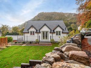 a house with a stone fence in front of a yard at Pandy Newydd in Trefriw