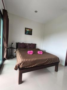 a bed with two pink slippers on top of it at Jigsaw Cafe & Resort in Ban Na We