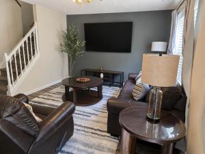 a living room with leather furniture and a flat screen tv at Spacious 3BR Retreat Perfect for Groups Near Downtown in Raleigh