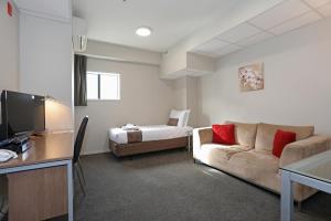 a hotel room with a couch and a bed at Ramada Encore by Wyndham Palmerston North in Palmerston North