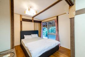 a bedroom with a bed and a window at Kume Guest House in Kumejima