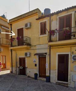 a yellow building with balconies and doors on a street at La Perla Di Noto in Noto