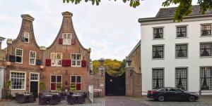 een bakstenen gebouw met een klokkentoren naast twee gebouwen bij 't Koetshuys in Heenvliet