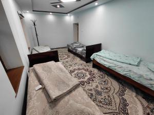 a room with two beds and a rug at Rahima's Guest House in Tadzhimi