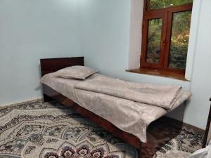 a small bed in a room with a window at Rahima's Guest House in Tadzhimi