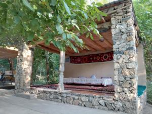 a bed in a stone building with a wooden roof at Rahima's Guest House in Tadzhimi +23 photos