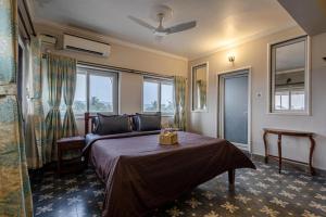 a bedroom with a bed and a couch and windows at The Baga Pescador in Baga
